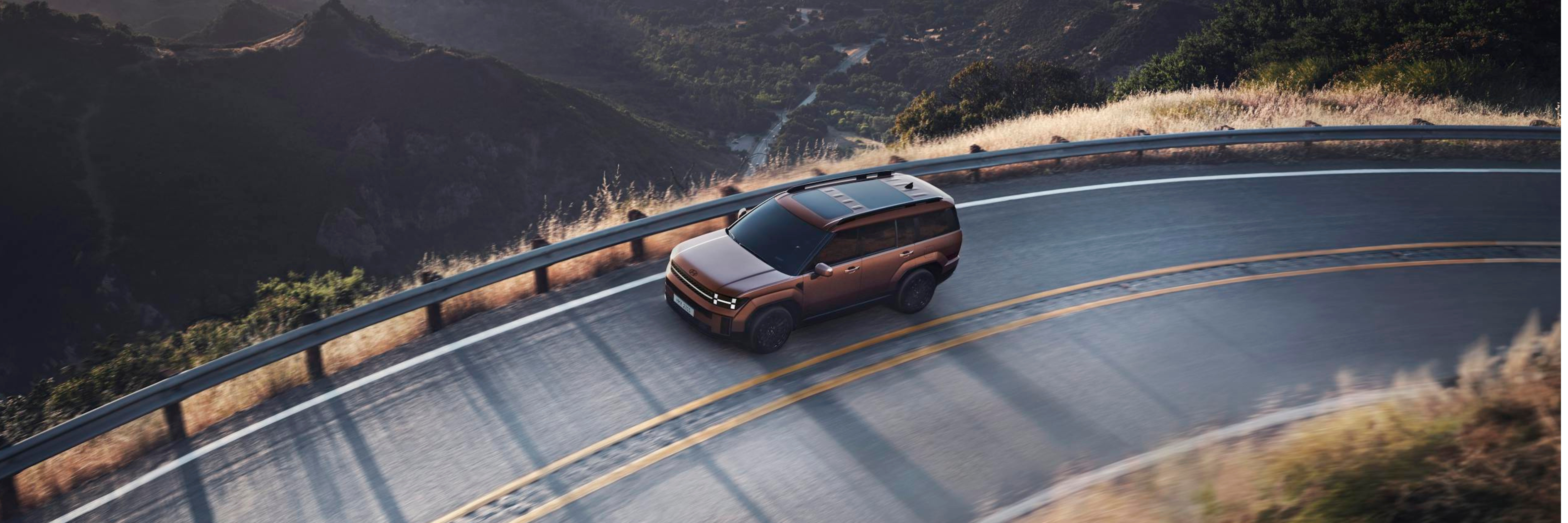 An SUV navigates a scenic mountainous road during sunset, offering breathtaking views and a sense of adventure.