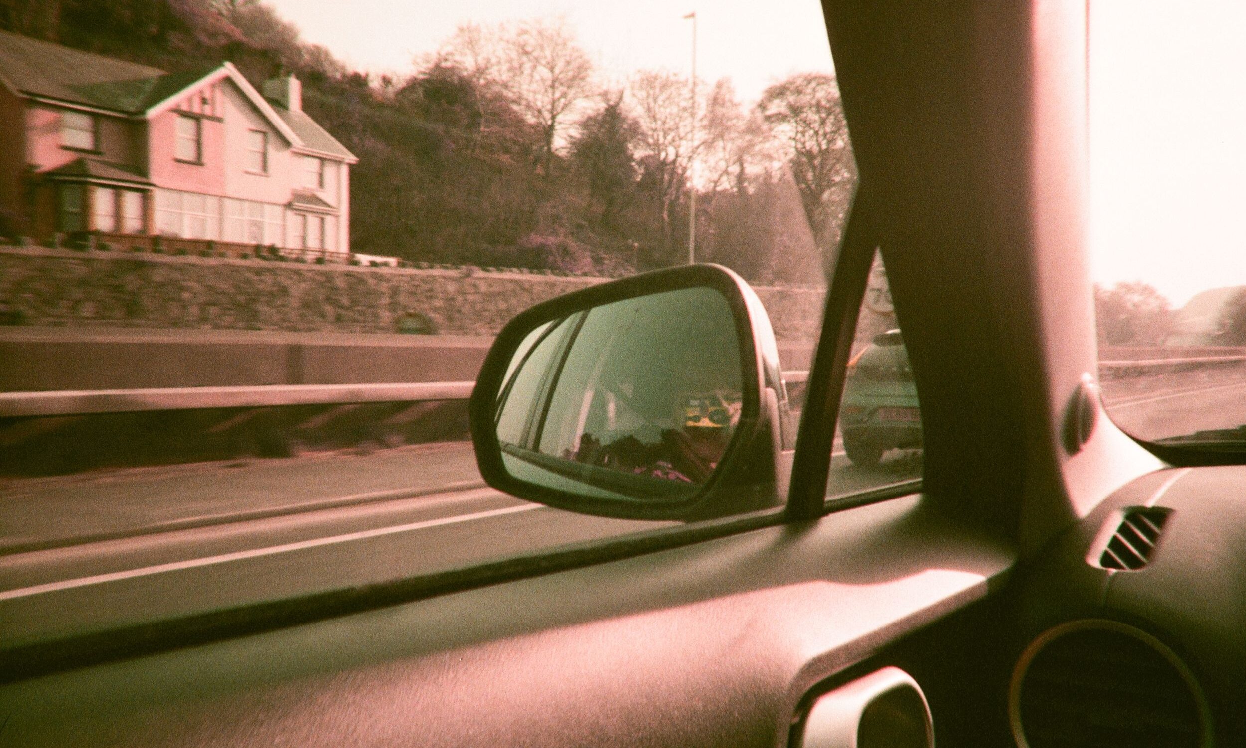 View from inside a car looking out at a countryside scene reflecting in the side mirror.